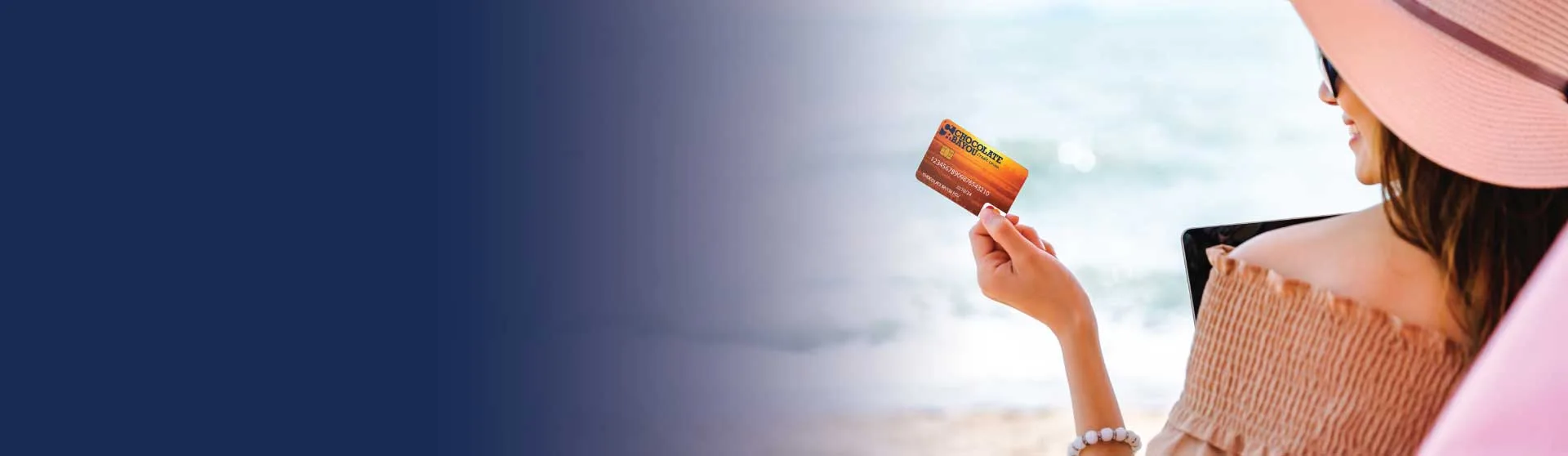 A lady holding her credit card on the beach.